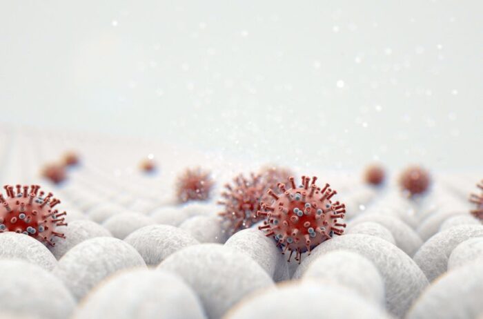 a microscopic close up view of a simple woven textile and a visible red coronavirus particle - 3d render